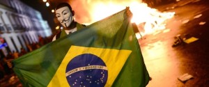 A demonstrator wearing a Guy Fawkes mask holds a Brazilian national flag during clashes in downtown Rio de Janeiro on June 17, 2013, after a protest against higher public transportation fares and the use of public funds to finance international football tournaments. Protesters in several major cities are up in arms over hikes in mass transit prices -- from $1.5 to $1.6 -- as well as over the $15 billion earmarked for the two sports events amid calls for more health and education funding. AFP PHOTO / CHRISTOPHE SIMON (Photo credit should read CHRISTOPHE SIMON/AFP/Getty Images)